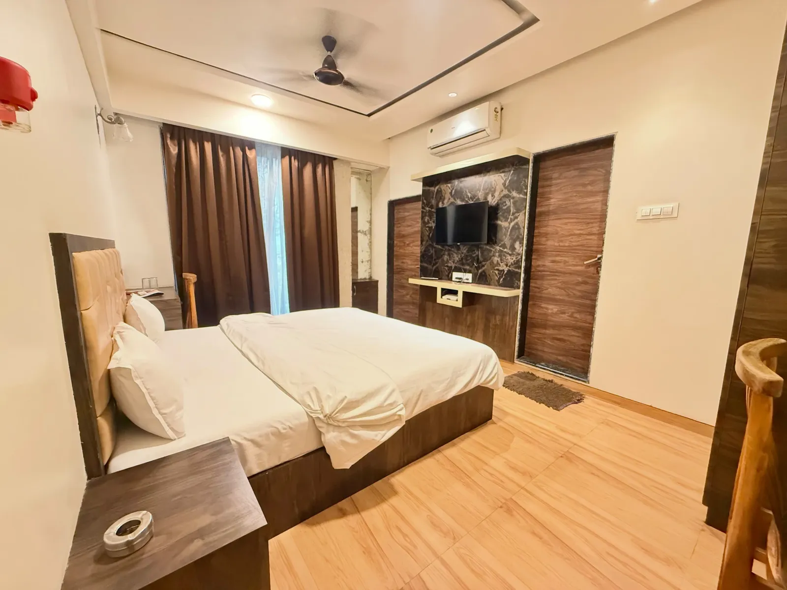 Deluxe AC room at Hotel Evershine with double bed, marble-finish TV wall, split AC and wooden flooring
